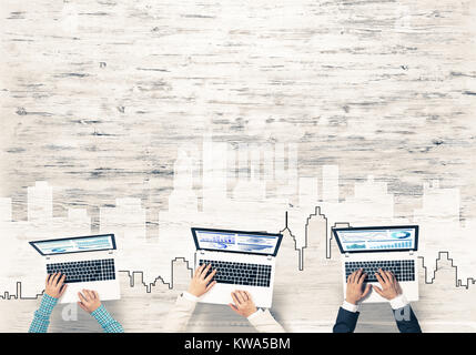 Un gruppo di tre persone con i dispositivi in mani lavorando insieme come simbolo del collegamento in rete e comunicazione Foto Stock