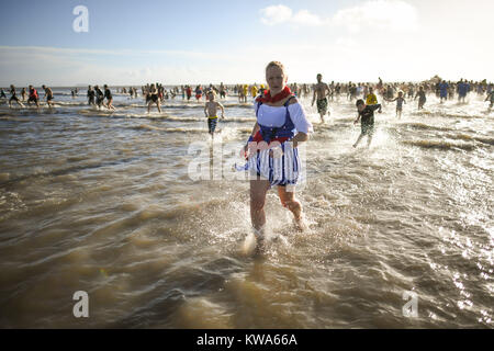 Nuotatori tuffo in mare a Barry Island il giorno di Anno Nuovo nuotare a Whitmore Bay, Vale of Glamorgan, South Wales, durante la trentaquattresima edizione annuale di Nuovo Anno Giorno nuotare, che inizialmente avviato quando cinque membri del Jacksons Bay Club bagnino deciso a scrollarsi di dosso i postumi della sbornia con un tuffo, da sommergere completamente se stessi per tre volte. Foto Stock