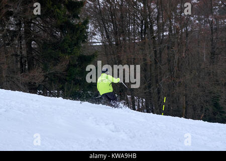 WINTERBERG, Germania - 16 febbraio 2017: l Uomo in camicia fluorescente prendendo un altalena su una pista a carosello sciistico Winterberg Foto Stock