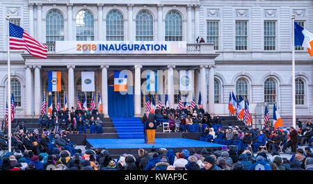 New York, Stati Uniti d'America. 1a gen, 2018. New York City il sindaco di Bill de Blasio (C) eroga il suo discorso di inaugurazione. De Blasio ha iniziato il suo secondo mandato come sindaco di usa la più grande città con una cerimonia all'aperto a City Hall Park al di sotto delle temperature di congelamento del 1 gennaio 2018. Credito: Enrique Shore/Alamy Live News Foto Stock