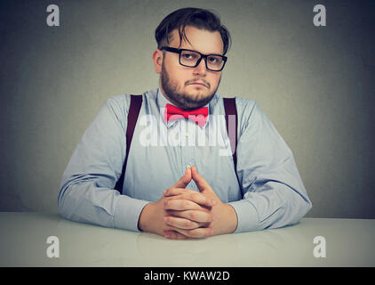 Grave uomo fiducioso in occhiali cercando prepotente in telecamera avente intervista. Foto Stock