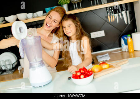 Madre e figlia preparazione frullato shealthy nella cucina moderna Foto Stock