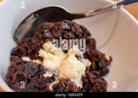 Una porzione del pudding natalizio con alcuni brandy il burro in una ciotola Foto Stock