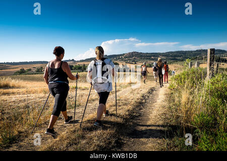 Casale Marittimo, Pisa, Italia - 12 Luglio 2017: gli escursionisti a piedi attraverso la campagna in estate piena di cipressi, balle di fieno e il cielo blu, panoramica Foto Stock