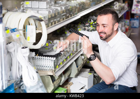 Ritratto di giovane uomo selezione di apparecchiatura in reparto per uso domestico Foto Stock
