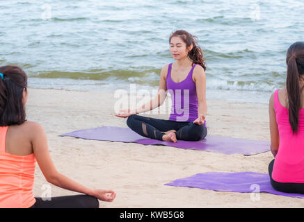 Classe di yoga in mare spiaggia di tramonto ,Gruppo di asia di persone facendo lotus pone con vongole emozione relax in spiaggia,Meditazione pongono,il benessere e la salute Foto Stock