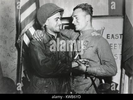 Stati Uniti Lt. William Robertson e sovietica Lt. Alexander Sylvashko abbraccio. Dietro di loro un segno, "East meets West' per celebrare la riunione del Soviet (Russo) e eserciti americani, vicino a Torgau, Germania. Aprile 25, 1945. Guerra mondiale 2. (BSLOC 2014 8 79) Foto Stock