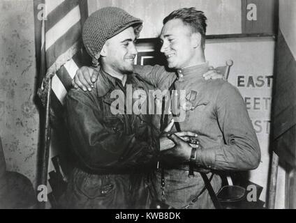 Stati Uniti Lt. William Robertson e sovietica Lt. Alexander Sylvashko abbraccio. Dietro di loro un segno, "East meets West' per celebrare la riunione del Soviet (Russo) e eserciti americani, vicino a Torgau, Germania. Aprile 25, 1945. Guerra mondiale 2. (BSLOC 2014 8 79) Foto Stock