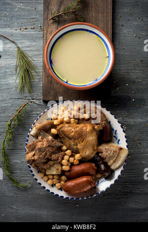 Cocido madrileno, tipico di Madrid, in Spagna, con la Zuppa servita in un recipiente di terracotta e la carne e le verdure utilizzate nel brodo servito in un vassoio Foto Stock