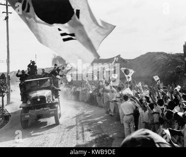 Stati Uniti Prima divisione di cavalleria truppe passano il tifo coreani a nord di Seoul sulla strada per la trentottesima parallelo. Un sud coreano sventola in primo piano con piccole bandiere sventolate in mezzo alla folla. Ca. Il 9 ottobre, 1950. Guerra di Corea, 1950-1953. (BSLOC 2014 11 64) Foto Stock