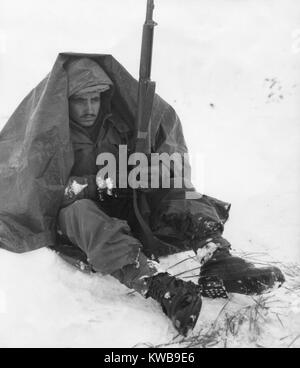 Soldato dell'U.S. Xix Reggimento di Fanteria usa il suo poncho di ottenere protezione dal vento pungente e freddo. Area Yoju gen. 10, 1951, dopo il ritiro delle forze ONU dalla Corea del Nord. Guerra di Corea, 1950-1953. (BSLOC 2014 11 71) Foto Stock