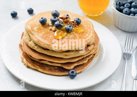 Vista ingrandita della pila di pancake con mirtilli, noci e miele sulla piastra bianca. Una gustosa colazione sana cibo. Posizione orizzontale Foto Stock