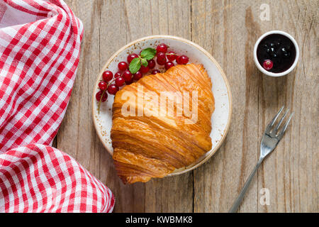 Croissant con frutti di bosco freschi e marmellata sul vecchio tavolo in legno. Vista superiore, orizzontale Foto Stock