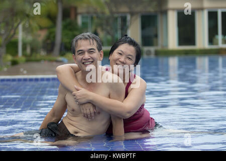 Coppie di senior asiatica di un uomo e di una donna felice a giocare in piscina di acqua Foto Stock
