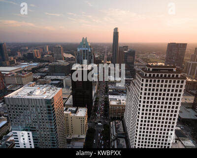 Persone uscire il centro di Austin come il sole colpisce l'orizzonte attraverso un labirinto di edifici alti Foto Stock