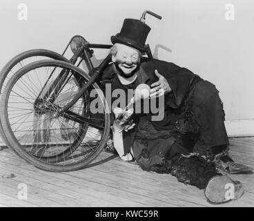 Hobo clown Joe Jackson reclino contro una bicicletta smontata al alla fiera mondiale di New York nel 1940. Il suo atto di pantomima incorporato comic stunt in bicicletta ed è stato assunto dal figlio Joe Jackson Jr. (BSLOC 2015 14 162) Foto Stock