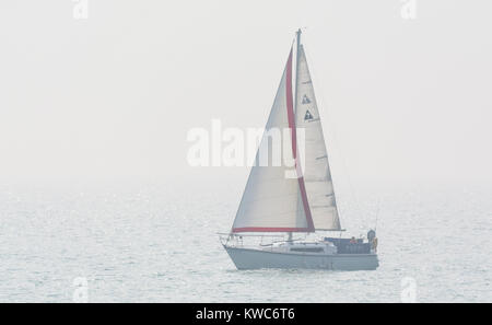 Piccolo yacht a vela sul mare di nebbia e nebbia. Foto Stock