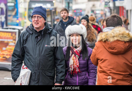 Un paio di origini etniche diverse passeggiate tenendo le mani in Inghilterra, Regno Unito. Foto Stock
