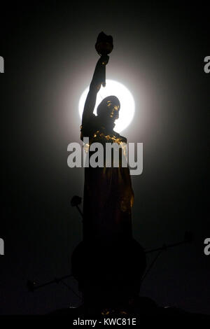 Il nuovo anno supermoon - noto anche come un lupo Luna - nella foto al suo massimo nel mezzo della notte del 2 gennaio dietro Kenny Mackay la scultura, chiamato la luce e la vita, che è stato recentemente collocato sulla sommità della ex co-operativa la società all'ingrosso sede su Morrison Street, Glasgow, Scozia. Foto Stock