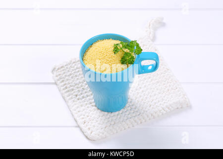 Tazza di couscous crudo su bianco tabella mat Foto Stock
