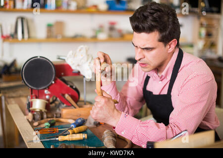 Esperto falegname concentrato il lavoro in officina con uno scalpello in mani Foto Stock