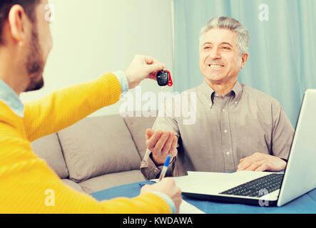 Uomo adulto e manager firmato il contratto di noleggio auto a casa e consegnare le chiavi Foto Stock