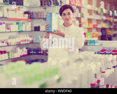 Femmina giovane farmacista suggerendo utili prodotti per la cura del corpo in farmacia Foto Stock