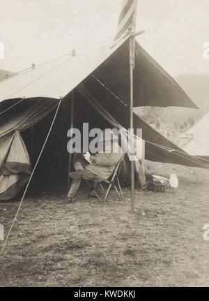 Theodore Roosevelt la lettura di fronte la sua tenda nella caccia camp, 3-4 giugno, 1909. Kijabe, British East Africa (Kenya) durante lo Smithsonian-Roosevelt spedizione africana (BSLOC 2017 8 5) Foto Stock