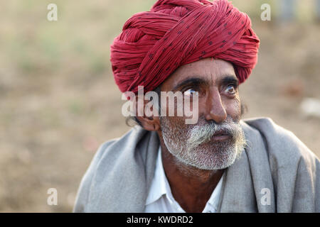 Di scena a Pushkar Camel Fair, ritratto di un operatore che indossa turbante rosso, Pushkar, Ajmer, Rajasthan, India Foto Stock