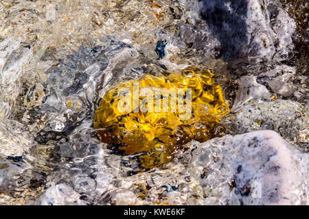 Il colore delle pietre sul fondale e le piccole onde del mare Foto Stock