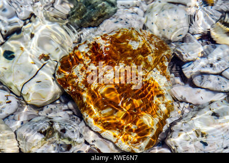 Il colore delle pietre sul fondale e le piccole onde del mare Foto Stock