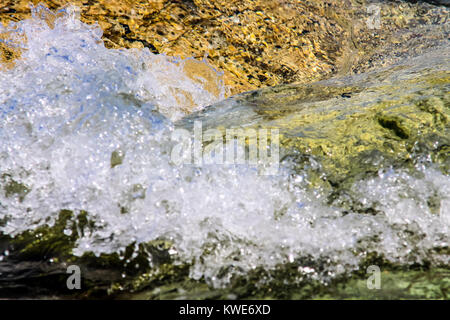 Il colore delle pietre sul fondale e le piccole onde del mare Foto Stock