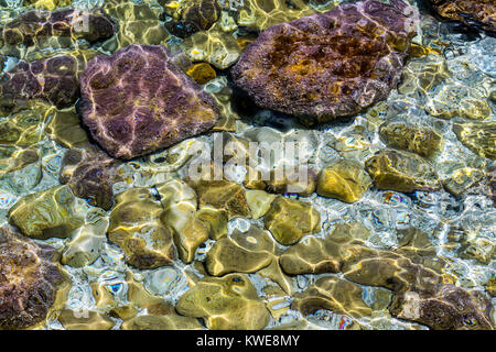 Il colore delle pietre sul fondale e le piccole onde del mare Foto Stock