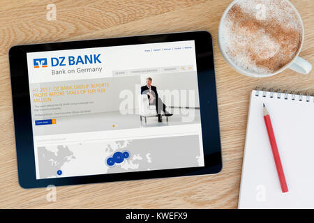 La DZ Bank sito web su un iPad dispositivo tablet, appoggiato su un tavolo di legno accanto a un blocco note, matita e tazza di caffè (editoriale solo) Foto Stock