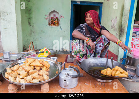 Una donna per la cottura samosa e peperoncino pakora al cibo hotel di Varanasi, India Foto Stock
