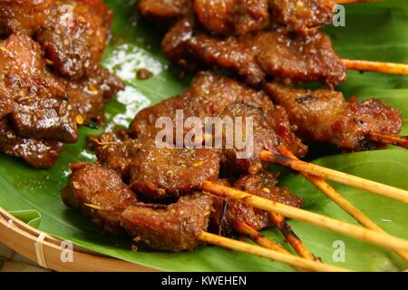 Sate Babi Bali. Balinese di maiale piccante saté; disposti su una foglia di banano. Foto Stock