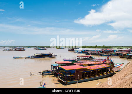 Barche lungo legati insieme e ormeggiato vicino al letto del fiume del lago Tonle Sap, per il trasporto dei turisti per Kampong Phluk villaggio galleggiante, Siem Reap, Cambogia Foto Stock