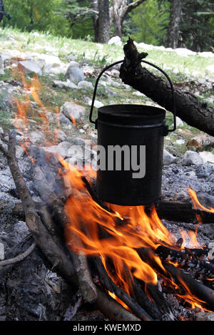 Appendere la benna nero sotto il fuoco nella foresta Foto Stock
