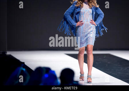 Modello femminile passeggiate in pista vestito blu durante una sfilata di moda. Passerella per sfilate di moda evento che mostra la nuova collezione di abbigliamento. Modello unico. Vestito blu. Foto Stock