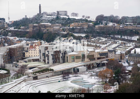 La neve cade sulla città di Edimburgo nel dicembre. Vista dello Skyline della città verso l'edificio del Parlamento scozzese a Holyrood e Calton Hill. Foto Stock