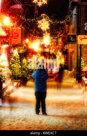 Una donna di fotografare le decorazioni di Natale e di neve fresca in Quebec City la Petit Champlain zona di notte in Rue Petit Champlain Foto Stock