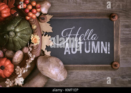 Lavagna con il testo "Ciao autunno"con l'autunno di decorazioni su legno. Vista superiore, tonica immagine. Foto Stock