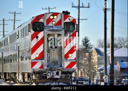 Inbound Metra treno il trasporto pendolari a Chicago lasciando il suburban Bartlett, Illinois stazione ferroviaria. Bartlett, Illinois, Stati Uniti d'America. Foto Stock