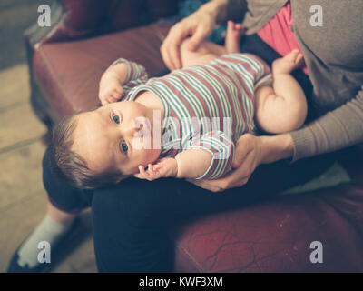 Un bambino felice sul grembo di sua madre a casa Foto Stock