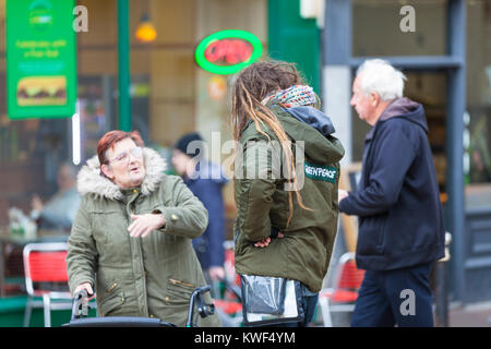 Un uomo con Dreadlocks che indossa una giacca di Greenpeace a domicilio di persone in Hastings Town Center, East Sussex Foto Stock