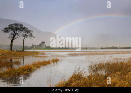 Kilchurn Castle e Loch Awe, Scozia in un giorno di pioggia in ottobre con un arcobaleno che figurano a emergere direttamente dal castello. Foto Stock