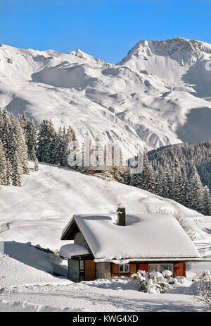 Piccola casa di legno in legno all'interno di un bellissimo paesaggio invernale ad Arosa, Svizzera Foto Stock