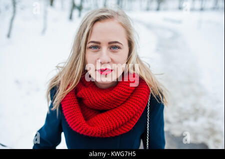 Portrai della ragazza bionda in sciarpa rossa e il cappotto sul giorno d'inverno. Foto Stock