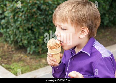 La foto in orizzontale del ragazzo biondo sono mangiare gelato in estate Foto Stock