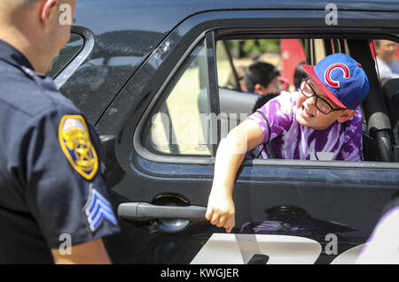 Moline, Iowa, USA. 13 Luglio, 2017. YMCA camper Parker Davis, 9, raggiunge per la maniglia esterna della porta di Moline Sgt di polizia. Jeremy settimane' cruiser mentre seduto nella parte posteriore della vettura al summer learning event presso il Centro iWireless di Moline giovedì, 13 luglio 2017. Un evento è stato tenuto per circa 800 bambini che partecipano in vari campi estivi in Quad-Cities di partecipare ad una varietà di attività in occasione della celebrazione del National Estate imparando giorno. Credito: Andy Abeyta, Quad-City volte/Quad-City volte/ZUMA filo/Alamy Live News Foto Stock